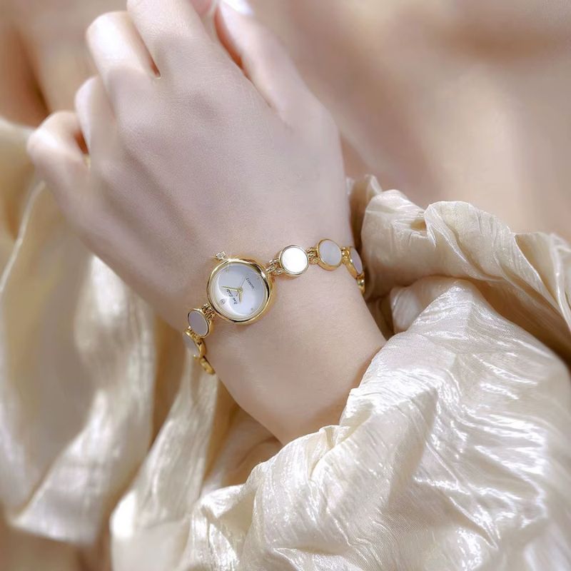 Złoty damski zegarek bransoletka z białą tarczą i akcentami masy perłowej