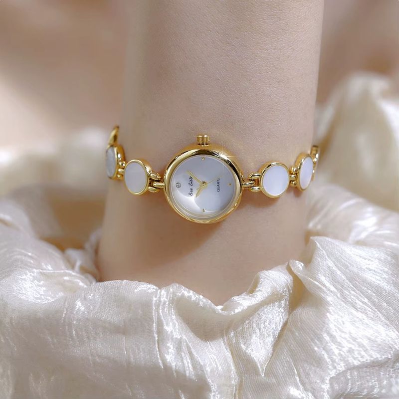 Elegancki damski zegarek mały z złotym paskiem, białą tarczą i akcentami masy perłowej