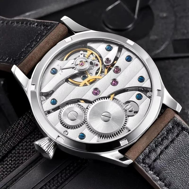 Srebrny szkieletowy zegarek z odsłoniętymi mechanizmami i akcentami z niebieskich i różowych kamieni szlachetnych na brązowym pasku ze skóry