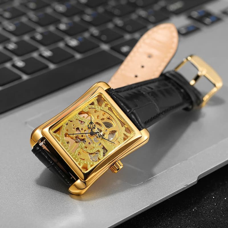 Złoty mechaniczny zegarek skeleton z czarnym paskiem i widocznymi mechanizmami