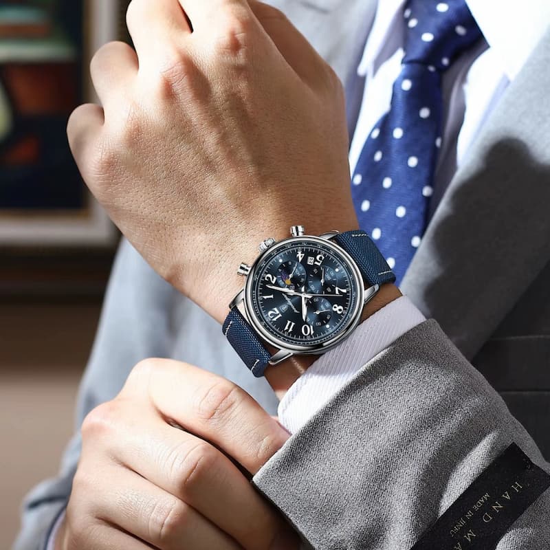 Srebrny chronograf z niebieską tarczą i paskiem, na męskim nadgarstku